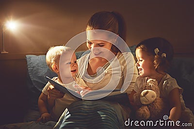 Happy family mother and children read a book in bed Stock Photo