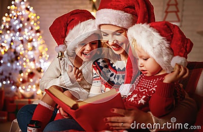 Family mother and children read a book at christmas near firep Stock Photo