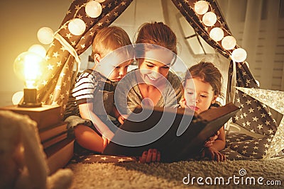 Happy family mother and children reading a book in tent at hom Stock Photo