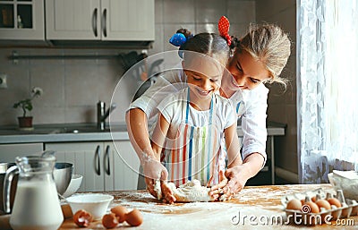 Happy family mother and daughter bake kneading dough in kitchen Stock Photo