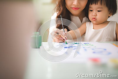 Happy family mother and daughter together paint. Asian woman helps her child girl. Stock Photo