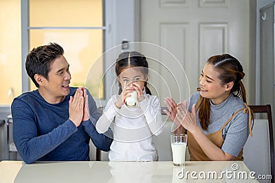 Happy family mother, father, child baby daughter having milk at home Stock Photo