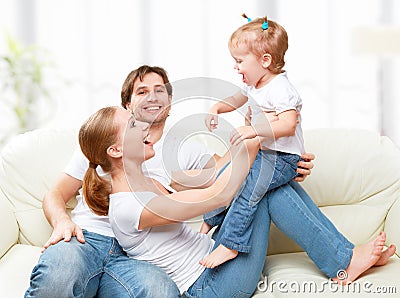 Happy family mother, father, child baby daughter at home on sofa playing and laughing Stock Photo