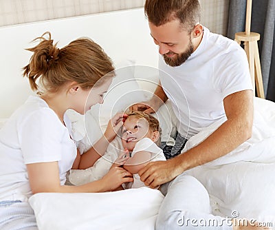 Happy family mother, father and child son laughing, playing, fights pillows and jumping in bed at home Stock Photo