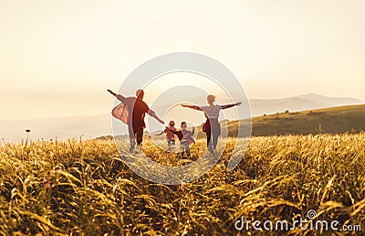 Happy family: mother, father, children son and daughter runing and jumping on sunset Stock Photo