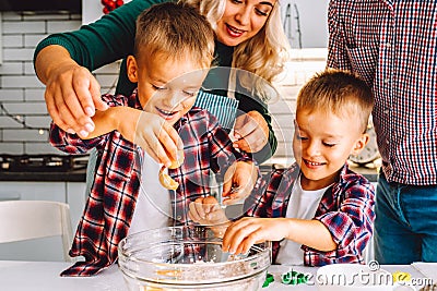 Happy family of mother, father and two children twins sons bake cookies in kitchen before Christmas Stock Photo