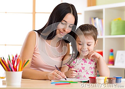 Happy family mother and kid daughter together paint. Woman helps child girl. Stock Photo