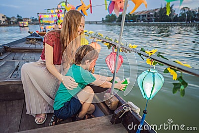 Happy family Mother and son of travelers ride a national boat on background of Hoi An ancient town, Vietnam. Vietnam Stock Photo