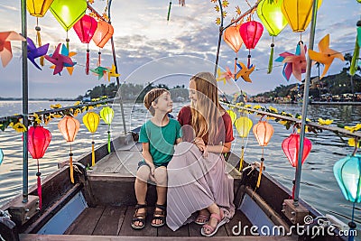 Happy family Mother and son of travelers ride a national boat on background of Hoi An ancient town, Vietnam. Vietnam Stock Photo