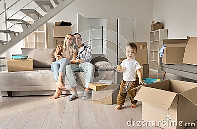 Happy family new home owners with child son in living room on moving day. Stock Photo