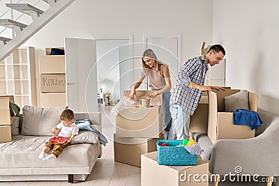 Happy family new home owners with child unpacking cardboard boxes on moving day. Stock Photo