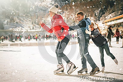 Happy family outdoor ice skating at rink. Winter activities Stock Photo