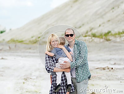 Happy family outdoors. Parents hold the son on hands. Stock Photo