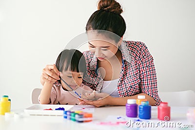 A happy family is painting. Mom help her daughter drawing Stock Photo