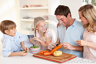 Happy family peeling vegetables in kitchen Stock Photo