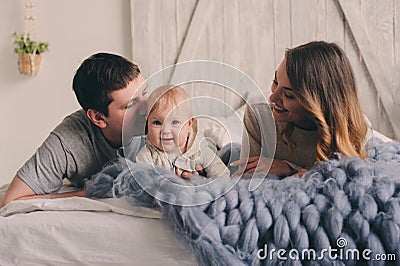 Happy family playing at home on the bed. Lifestyle capture of mother, father and baby Stock Photo