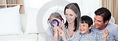 Happy family playing with a magnifying glass Stock Photo