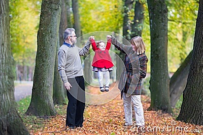 Happy family playing with toddler girl in autumn park Stock Photo