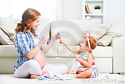 Happy family pregnant mother and child daughter preparing clothi Stock Photo