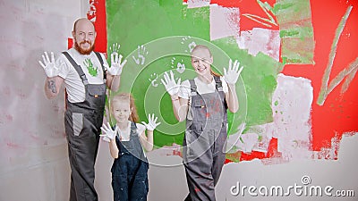 Happy family are putting their white handprints on a green wall - looking in the camera Stock Photo