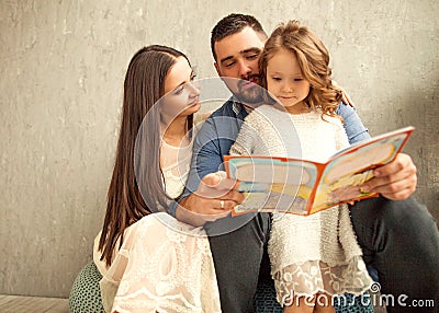Happy family reading a book to her daughter. Mothers Day. Stock Photo
