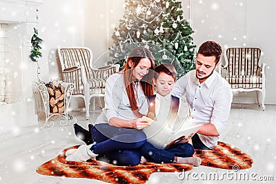 Happy family reading Christmas fairy tales near the Xmas tree. Living room decorated by Christmas tree and present gift box Stock Photo