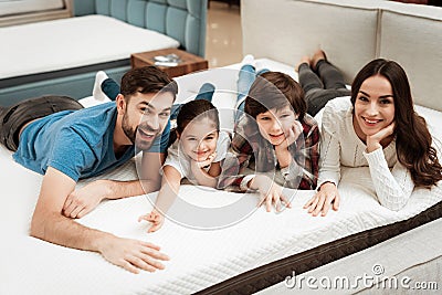 Happy family is relaxing on mattress in orthopedic furniture store. Big family check softness of mattress Stock Photo