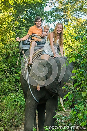 Happy family riding on an elephant, woman sitting on the elephant`s neck Stock Photo