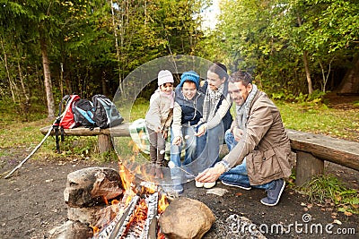 Happy family roasting marshmallow over campfire Stock Photo