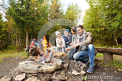 Happy family roasting marshmallow over campfire Stock Photo