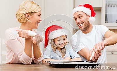 Happy family in santa helper hats making cookies Stock Photo