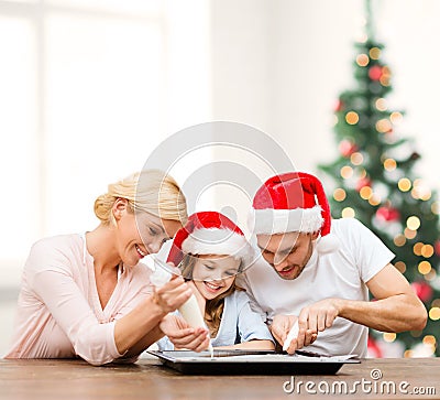 Happy family in santa helper hats making cookies Stock Photo