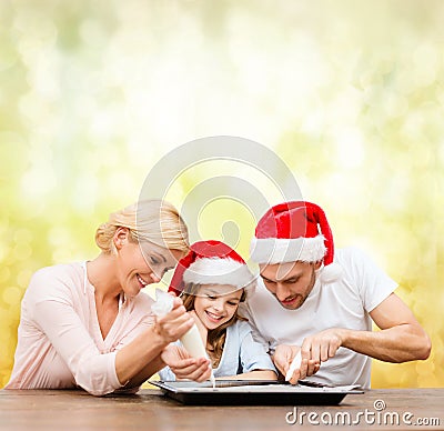 Happy family in santa helper hats making cookies Stock Photo