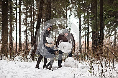 Happy family sculpts snowman. Stock Photo