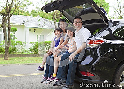 Happy family sitting in the car and their house behind Stock Photo