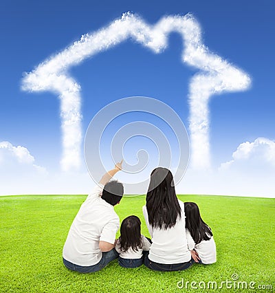 Happy family sitting on a meadow with house of clouds Stock Photo