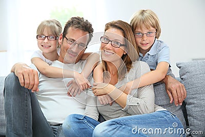 Happy family sitting on sofa wearing eyeglasses Stock Photo