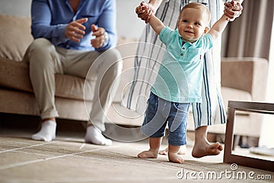 Happy family -Smiling baby boy making first steps Stock Photo