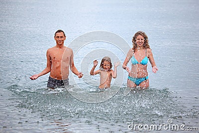 Happy family splashes water hands standing in sea Stock Photo