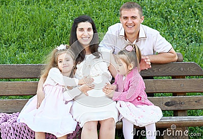 Happy family in summer city park outdoor, pregnant woman, parent and children, bright sunny day and green grass, beautiful people Stock Photo