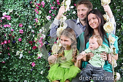 Happy family on swing look toward near hedge Stock Photo