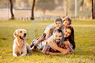 Happy family with two children lying in a pile on grass with dog sitting Stock Photo