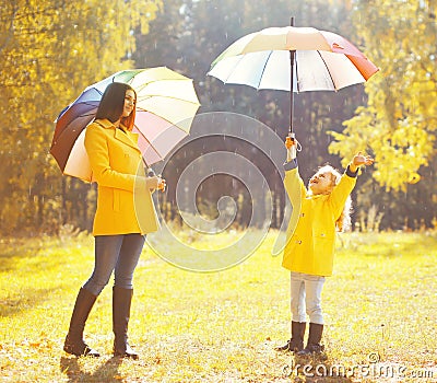 Happy family with umbrellas in sunny autumn rainy day Stock Photo
