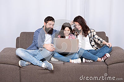 Happy family using laptop. Stay online. little girl with parents. mother and bearded father with daughter looking at Stock Photo