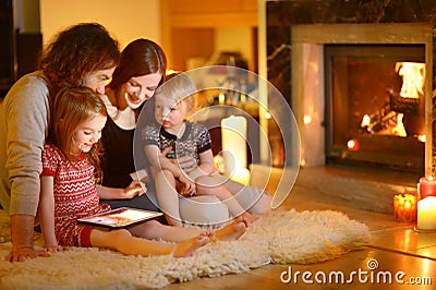 Happy family using a tablet pc by a fireplace Stock Photo