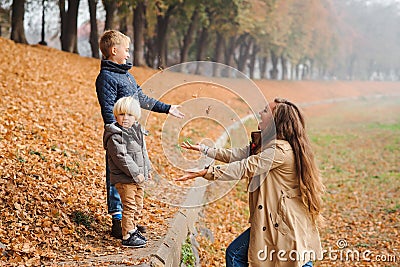 Happy family walking in an autumn park. Mother and children playing with fallen leaves. Love, relationship, family, season and Stock Photo