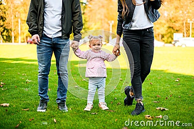 Happy family walking on the green lawn holding baby hands Stock Photo