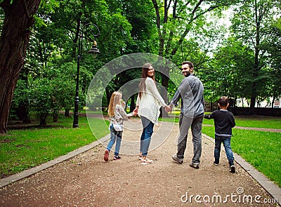 Happy family walking holding hands in green city park Stock Photo