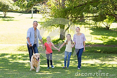 Happy family walking in the park with their dog Stock Photo