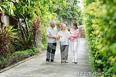 Happy family walking together in the garden. Old elderly using a walking stick to help walk balance. Concept of Love and care of Stock Photo